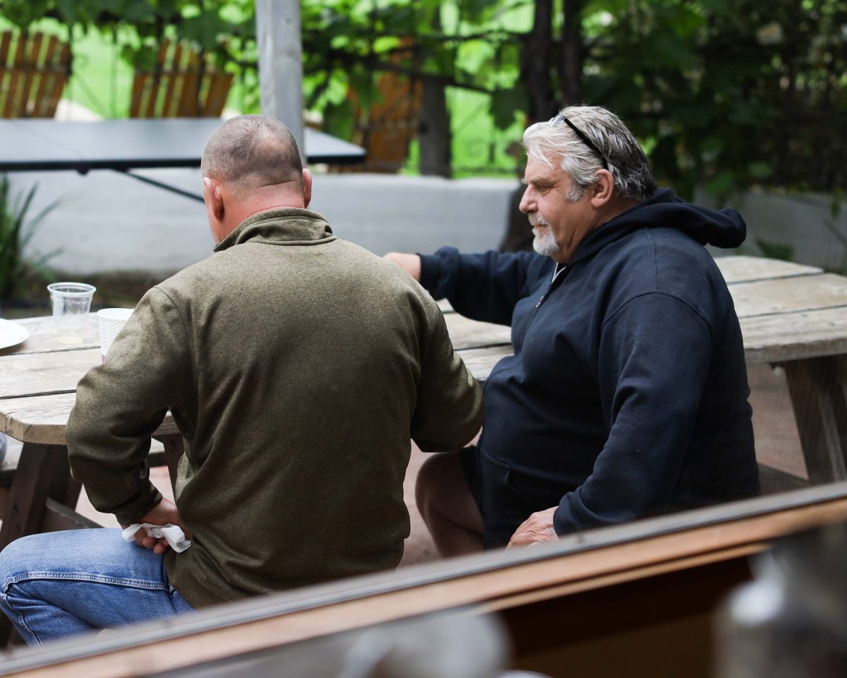 Two men sitting at a picnic table outside engaged in a psychotherapy session